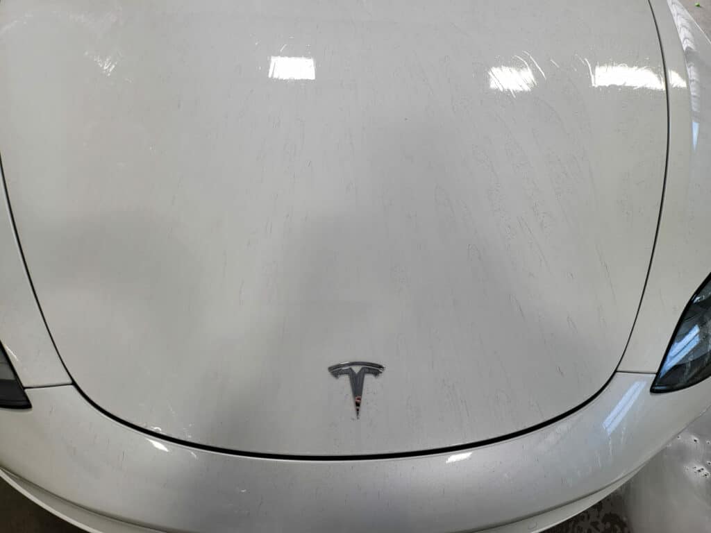 White tesla hood with CarPro iron x fallout remover applied. You can see the purple lines left as the iron is dissolved.