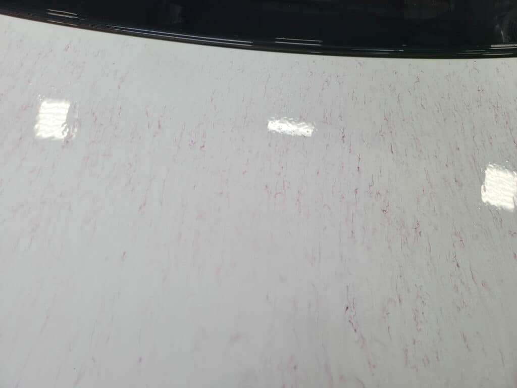 White tesla with CarPro iron x fallout remover applied. Heavy iron contamination section. You can see the purple lines left as the iron is dissolved.